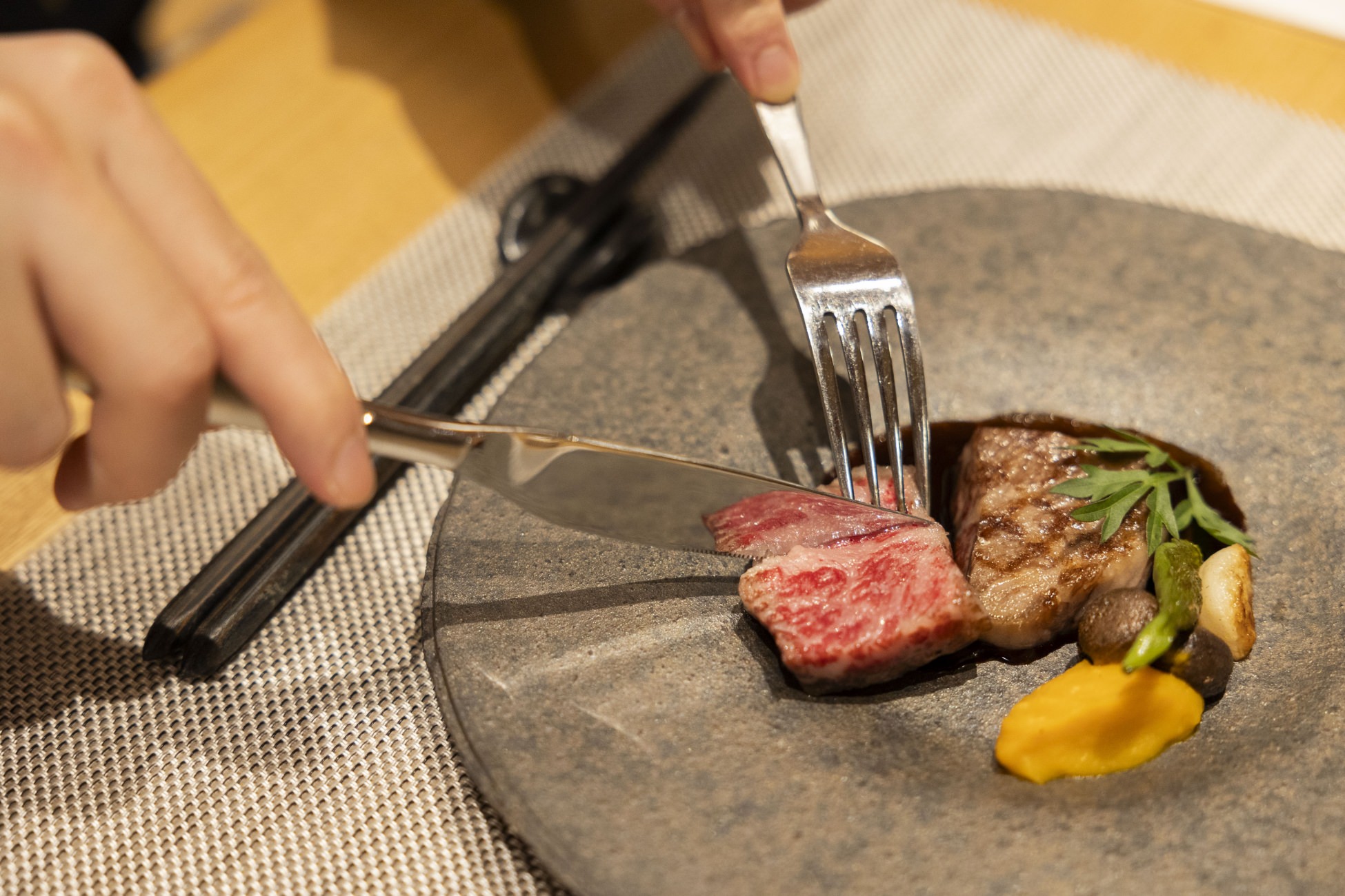 NIPPONIA HOTEL 伊賀上野 城下町のレストランLE UNのディナーメニュー ステーキを食べる様子