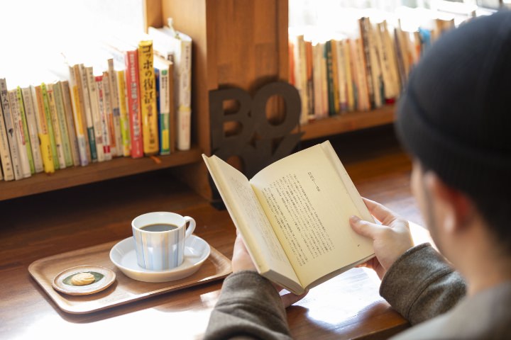 maco maretsさんが月明かりの書斎で本を読む様子